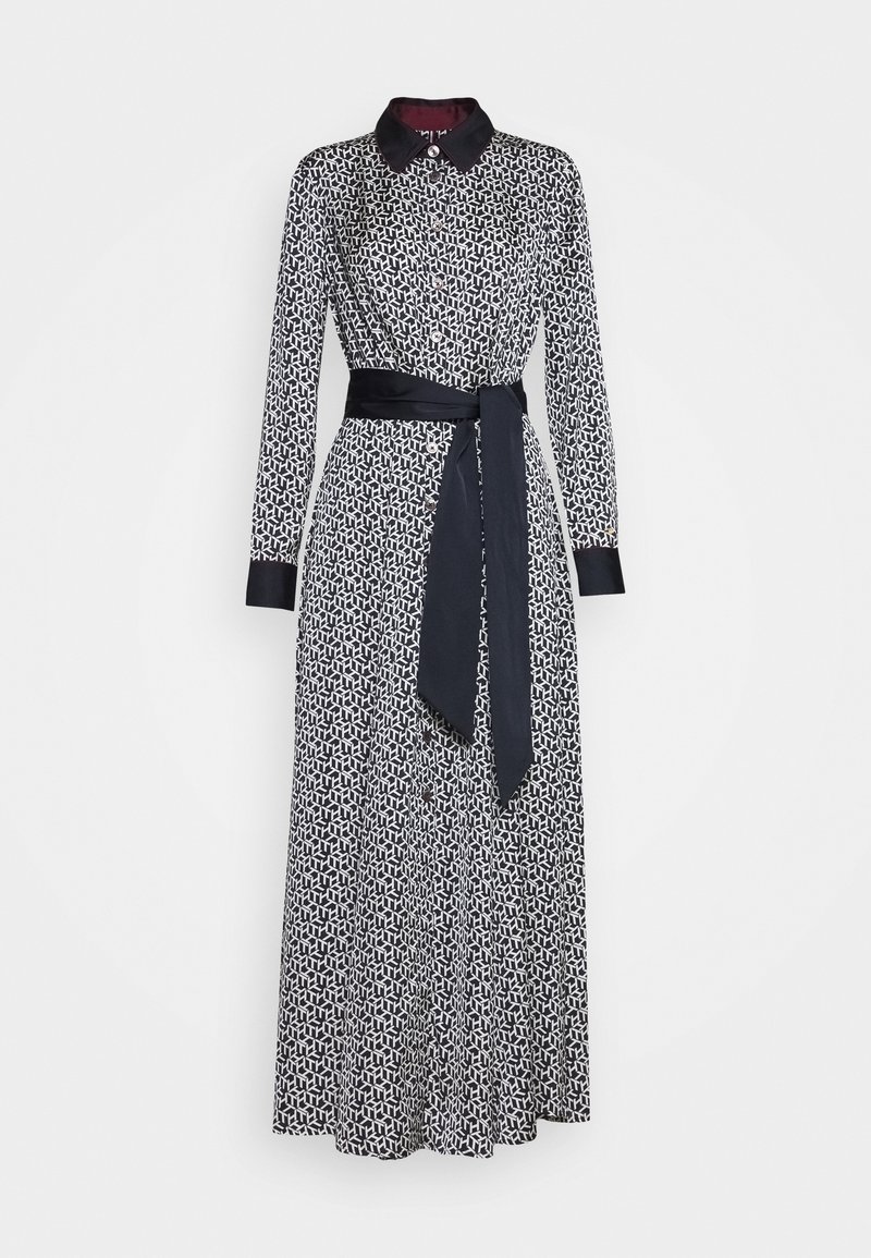 Robe à manches longues noire et blanche à motifs, avec col noir, détails aux poignets, fermeture boutonnée sur le devant et ceinture nouée noire à la taille.