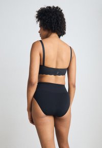 Black bra with lace accents and thin straps paired with high-waisted black underwear. Smooth texture, seamless design, and no visible hardware.
