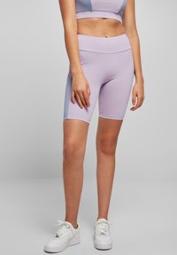 Heledat lilla spordipüksid, mis on valmistatud venivast kangast, kõrge v öökohaga ja siledapinnaline. Sobitatud valgete tennistega.