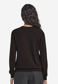 Brązowy sweter wykonany z miękkiego materiału, z okrągłym dekoltem i długimi rękawami, z dopasowanym wykończeniem w talii.