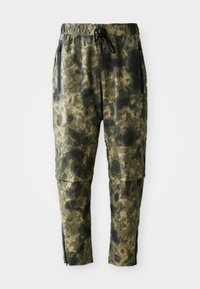Cargo bukser i grøn camouflage mønster, med elastisk talje, lynlåslommer og tætsiddende ben med lynlåse ved manchetterne.