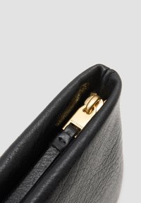 Zwarte leren clutch met een gestructureerde afwerking, gouden hardware en een ritssluiting. Het interieur bevat een gladde voering en een merklabel.