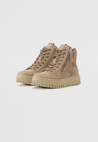 Baskets montantes en daim tan avec fermeture à lacets, zip latéral et semelle en caoutchouc beige striée. Présentent une texture lisse et un design minimaliste.