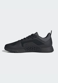 Zapatillas deportivas negras con una parte superior de malla texturizada, suela de goma sólida y acentos de corte geométrico en los laterales. Cierre con cordones y diseño de corte bajo.