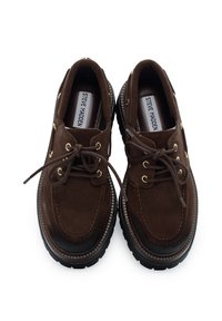 Scarpe in suede marrone con un design arrotondato, occhielli dorati e suole in gomma nera. Lacci in suede coordinato. Progettate per l'abbigliamento casual.