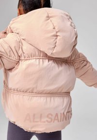 Giacca puffo rosa con un ampio cappuccio, vita e polsini elasticizzati, con la scritta "ALLSAINTS" in una stampa sottile sul retro.