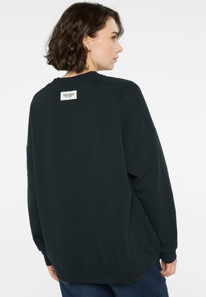 Dunkelgrünes, übergroßes Sweatshirt mit Rundhalsausschnitt, gerippten Bündchen und Saum. Verfügt über ein Branding-Etikett am oberen Rückenausschnitt. Weicher, strukturierten Stoff.