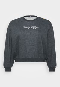Grå kortärmad sweatshirt med långa ärmar, med "Tommy Hilfiger" broderat i vitt och guldknappar på axeln. Blandmaterial av bomull.