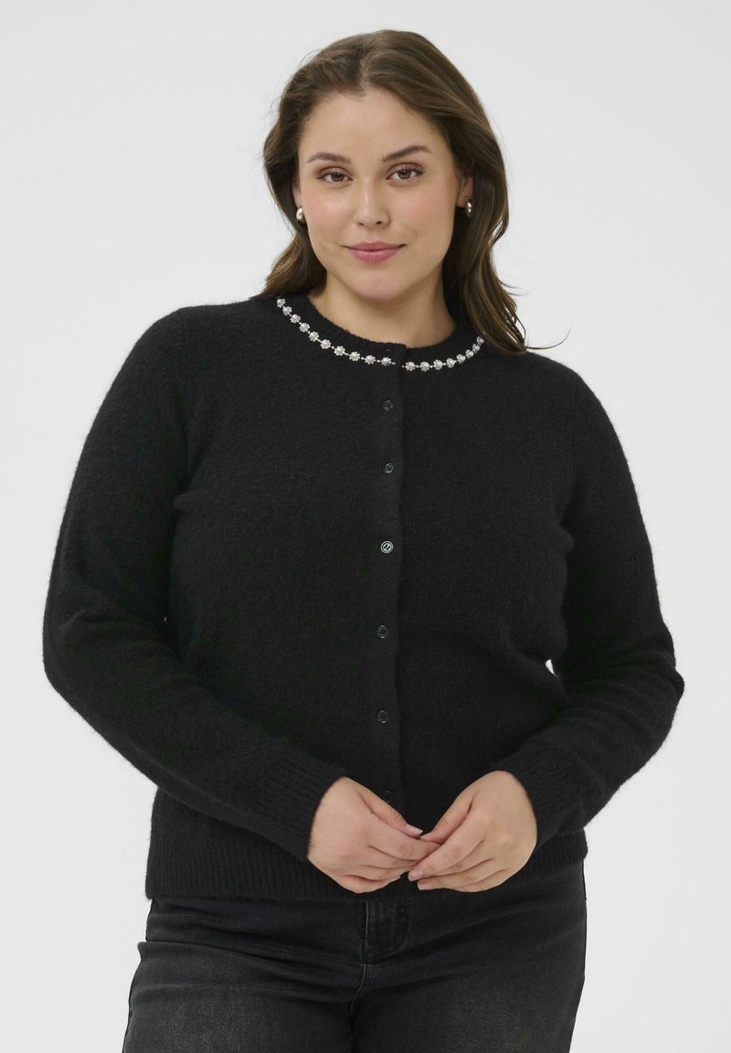 Cardigan noir à boutonnière fabriqué en tissu doux et texturé, avec une finition décorative en perles autour du col et des poignets côtelés.