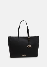 Sac fourre-tout noir Calvin Klein en simili cuir lisse, doté de deux poignées, d'un charm logo doré et d'une fermeture éclair sur le dessus.