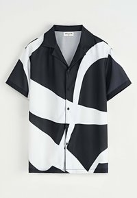 Chemise à manches courtes en noir et blanc, présentant un motif abstrait audacieux. Tissu doux, col classique et fermeture à boutons.