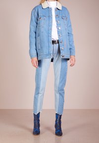 Jeansjacka med fårskinnskrage, ljusblå tvätt, två bröstfickor, kombinerad med blå gradient jeans och blå klackstövlar.