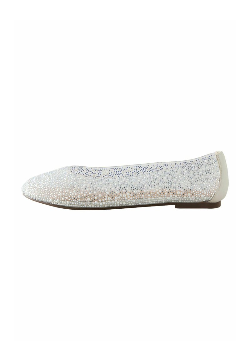 Chaussure plate avec une tige blanche texturée ornée de petites perles, un bout arrondi et un talon beige. La semelle est plate et marron.