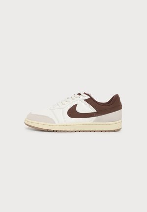 Madalad tennised valge ja beežika nahaga, pruunide aktsentide, valgete paelte ja pruuni Nike swoosh logo küljes.
