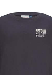 Maglietta in cotone blu scuro con collo a giro. Presenta la scritta bianca "RETOUR JEANS" in orientamento orizzontale e verticale sulla parte sinistra del petto.