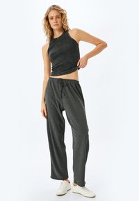 Grå ribbet crop top med høj krave, parret med løse grå bukser med elastisk talje og snøre detalje.