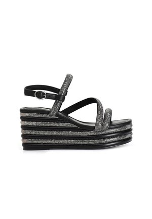 Sandales plateformes noires avec une semelle empilée, ornées d'accents métalliques argentés et de fines lanières. Bride de cheville réglable pour un ajustement parfait.