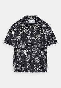 Kortärmad svart skjorta med ett vitt blommönster, knappstängd framtill och en avslappnad passform. Tillverkad av lättviktsmaterial.
