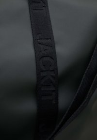 Borsa impermeabile nera con finitura testurizzata, dotata di una distintiva tracolla nera intrecciata con lettering embossato.