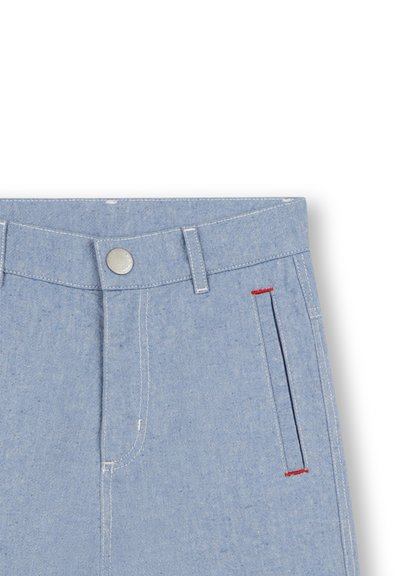 Lichtblauwe denim broek met een metalen knoopsluiting, riemlussen en een zijzak met rode stikseldetails. Glad textuur.