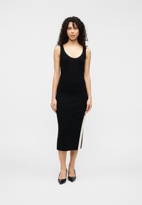 Μαύρο midi φόρεμα χωρίς μανίκια με στρογγυλή λαιμόκοψη, διαθέτει πλαϊνή σκίσιμο και μπεζ λεπτομέρειες. Κατασκευασμένο από λείο, ελαστικό ύφασμα.