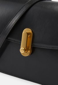 Bolsa de mão de couro preto com formato retangular, textura suave e um fecho dourado com detalhe de fecho.
