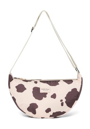 Halvemaanvormige tas in crème met een bruine koeienprint, gemaakt van stof. Heeft een ritsluiting en een verstelbare riem voor crossbody-draagstijl.