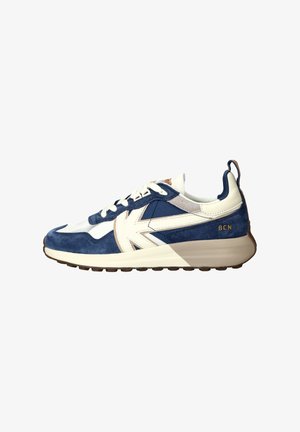 Blue suede and white textile sneaker with beige accents, featuring a prominent logo and textured rubber sole. Slip-on design with lace closure.