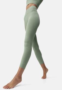 Lys grønne leggins med høy midje. Glatt stoff med strukturert søm og en tettsittende design, perfekt for treningstøy eller hverdagsbruk.