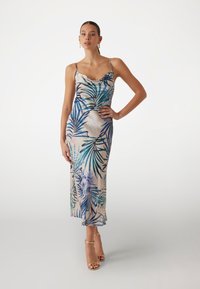 Abito midi in satin con sottili spalline, caratterizzato da un motivo di foglie tropicali blu e verdi su uno sfondo beige chiaro. Texture liscia.