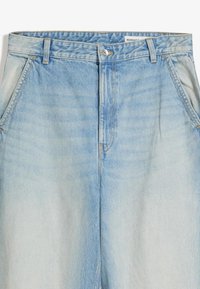 Svetlo modre kavbojke iz jeansa z izbledele zaključkom, s sprednjim zadrgo, zankami za pas in poševnimi sprednjimi žepi, ki kažejo gladko teksturo.