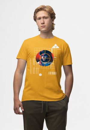 Gul bomulds T-shirt med et grafisk design med et blåt og rødt cirkulært mønster og tekst, der viser et portræt af en kvinde.