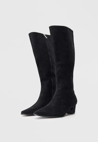 Botas pretas de camurça até ao joelho com bico fino e um salto bloco baixo. Apresentam um fecho éclair prateado de lado para um fácil calçar.