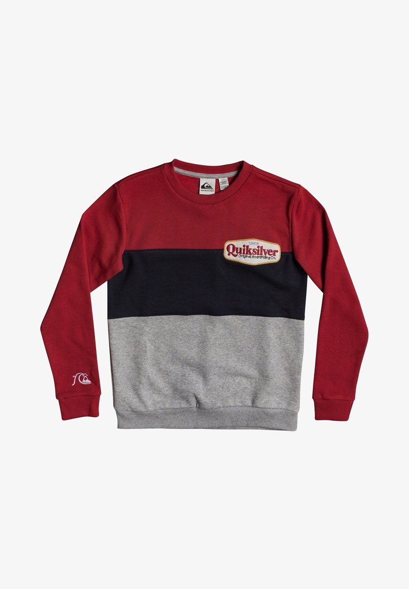 Sweat-shirt à manches longues avec des blocs de couleurs rouge, noir et gris, et un patch logo Quiksilver sur la poitrine et la manche.