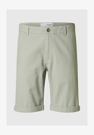 Jasnozielone bawełniane szorty z zawiniętym dołem, z zapięciem na guziki i szlufkami na pasek. Zaprojektowane z myślą o codziennym noszeniu, o schludnym wykończeniu.