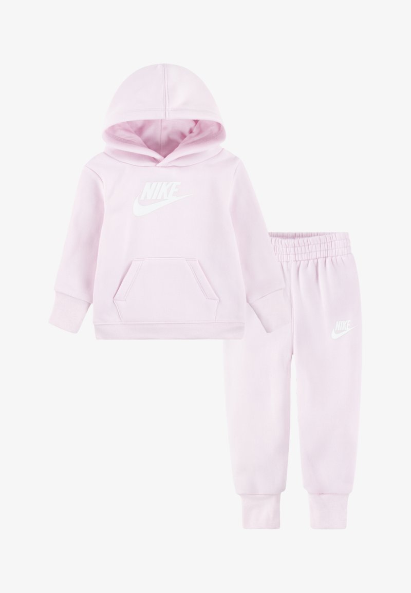 Conjunto de sweatshirt e calças de fato cor-de-rosa feito de tecido macio, apresentando um bolso frontal e um logotipo da Nike branco em ambas as peças. A sweatshirt tem capuz com cordão.