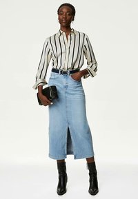 Langærmet skjorte med striber i creme og marineblå, kombineret med en lyseblå denimnederdel med en slids foran. Sort bælte og clutch fuldender outfittet.