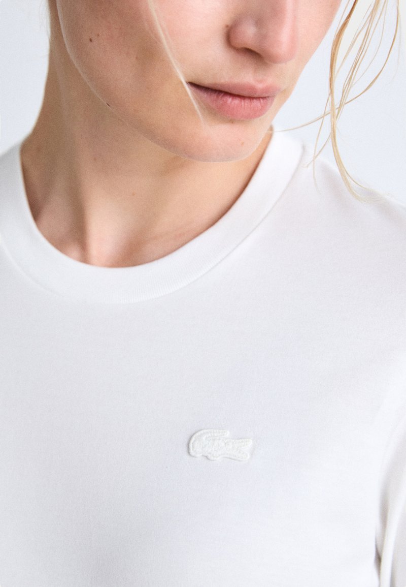 Biała koszulka z krótkim rękawem z miękkiej bawełny, z wyhaftowanym białym logo na piersi, o klasycznym okrągłym dekolcie.
