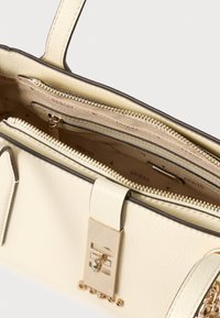 Geantă albă din piele ecologică cu accesorii aurii, textură netedă, compartimente multiple și închidere cu fermoar. Interiorul este căptușit cu material textil cu logo.