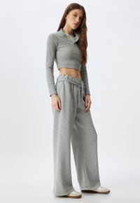 Grijze cropped langsl sleeve top met een ritskraag, gecombineerd met comfortabele grijze sweatpants met een elastische tailleband en trekkoord.