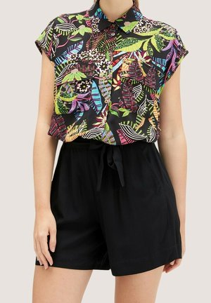 Skjorte med kap-ærmer og knapper med farverigt tropisk blad- og blomsterprint, parret med højtaljede sorte shorts bundet i taljen.