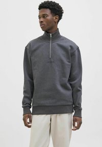Dark gray quarter-zip pullover with a soft texture, ribbed cuffs and hem, featuring a subtle logo on the chest.
