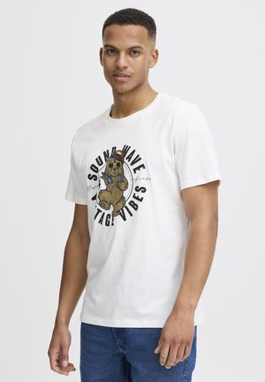 Hvid bomulds t-shirt med en grafisk illustration af en bjørn iført solbriller, med teksten "SOUND WAVE VINTAGE VIBES" i sort.