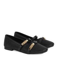 Mocassins noirs avec une tige en maille texturée, dotés de deux fines lanières noires avec des accents dorés à l'avant et d'une semelle plate.