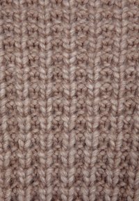Tessuto lavorato a maglia beige con un motivo testurizzato caratterizzato da righe verticali alternate e un aspetto morbido e peloso.