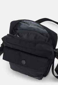 Czarna torebka crossbody z zamkiem błyskawicznym, przednią kieszenią na klapkę i wewnętrznymi kieszeniami. Posiada teksturowaną powierzchnię oraz regulowany pasek.
