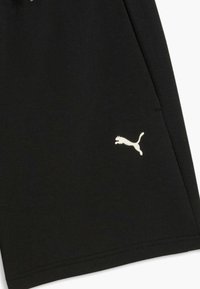 Shorts en tissu noir avec un petit logo Puma blanc près de l'ourlet sur le côté droit et un panneau latéral texturé.