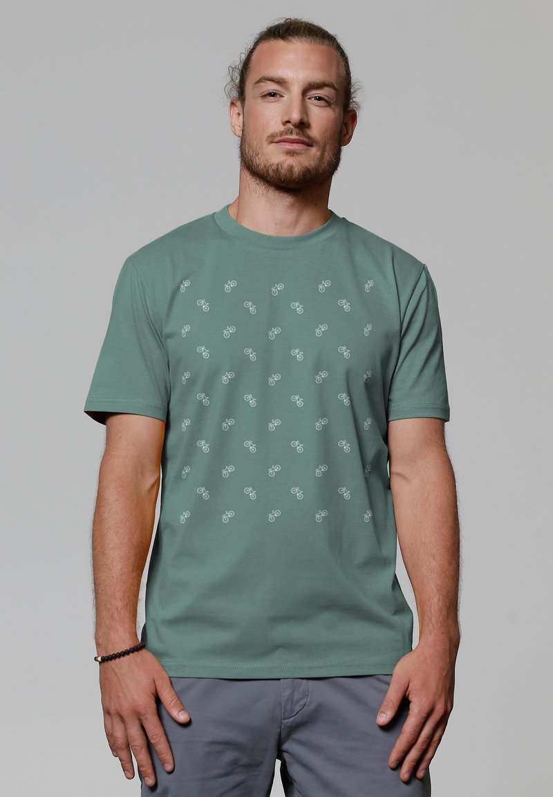 T-shirt en coton vert avec un motif graphique de bicyclettes en gris clair. Encolure ronde classique et manches courtes.