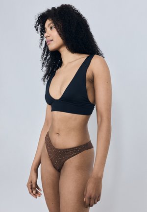 Crni bikini top s dubokim V izrezom i širokim naramenicama, uparen s smeđim bikini donjim dijelom ukrašenim progresijom metalnih zakovica.