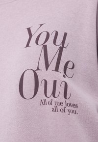 Fioletowy sweter z grafiką z napisem "You Me Oui" oraz "All of me loves all of you" w kontrastowych ciemnych literach.
